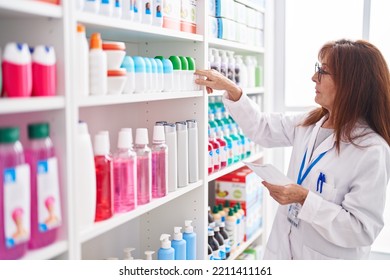 Middle Age Woman Pharmacist Holding Bottle Reading Prescription At Pharmacy