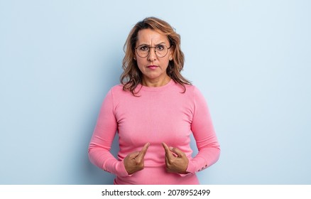 Middle Age Woman Pointing To Self With A Confused And Quizzical Look, Shocked And Surprised To Be Chosen