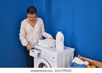 Middle age woman pouring detergent on washing machine at laundry room - Shutterstock ID 2311799235