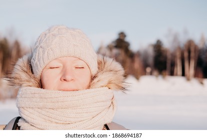 Middle Age Woman Relaxing Under Winter Sun. Woman With Eyes Closed Wearing Knitted Hat And Scarf Enjoying The Sun. Toned Picture. Selective Focus