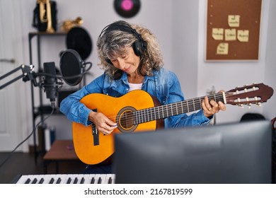 Middle age woman singer singing song playing guitar at music studio - Powered by Shutterstock