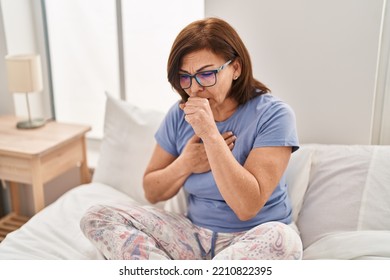 Middle age woman sitting on bed coughing at bedroom - Powered by Shutterstock