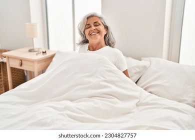 Middle age woman smiling confident sitting on bed at bedroom - Powered by Shutterstock