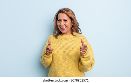 middle age woman smiling with a positive, successful, happy attitude pointing to the camera, making gun sign with hands