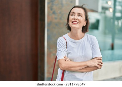 Middle age woman standing with arms crossed gesture at street - Powered by Shutterstock