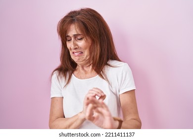 Middle Age Woman Standing Over Pink Background Disgusted Expression, Displeased And Fearful Doing Disgust Face Because Aversion Reaction. 