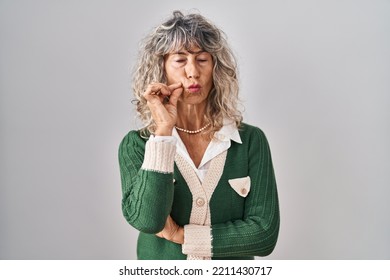 Middle Age Woman Standing Over White Background Mouth And Lips Shut As Zip With Fingers. Secret And Silent, Taboo Talking 