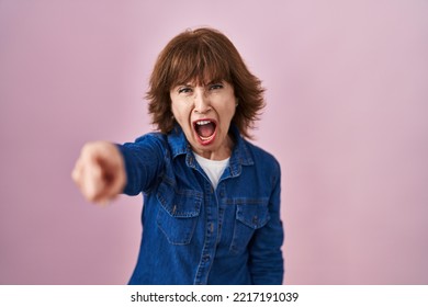 Middle age woman standing over pink background pointing displeased and frustrated to the camera, angry and furious with you  - Shutterstock ID 2217191039