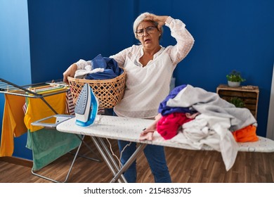 Middle Age Woman Stressed Doing Chores At Laundry Room