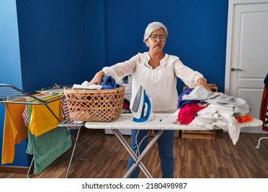 Middle Age Woman Stressed Doing Chores At Laundry Room