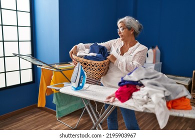 Middle Age Woman Stressed Doing Chores At Laundry Room