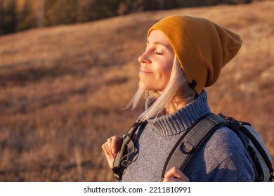 Middle age woman stretching arms breathing fresh air in a forest in autumn. Female traveler spends their vacations going hiking - Powered by Shutterstock