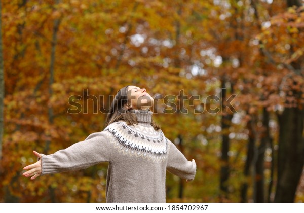 Middle age woman stretching arms breathing fresh\
air in a forest in\
autumn