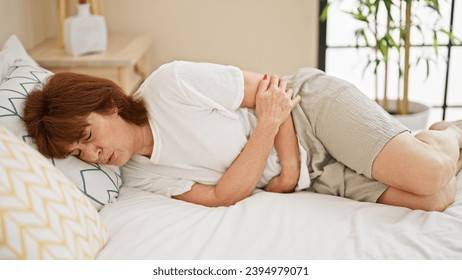 Middle age woman suffering for stomach ache lying on bed at bedroom - Powered by Shutterstock