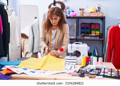 Middle age woman tailor cutting cloth at clothing factory - Powered by Shutterstock