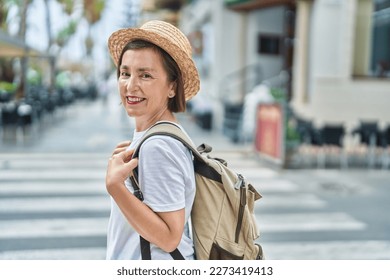 Middle age woman tourist smiling confident wearing backpack at street - Powered by Shutterstock