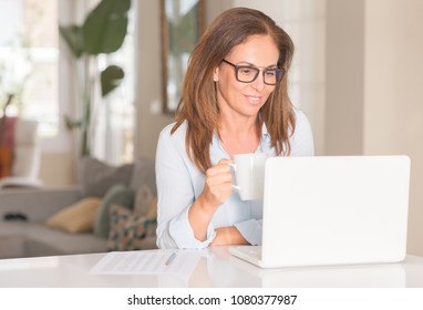 Middle Age Woman Using Computer And Drinking Coffee, Indoor