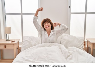 Middle age woman waking up stretching arms at bedroom - Powered by Shutterstock