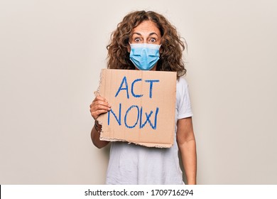 Middle Age Woman Wearing Coronavirus Protection Mask Holding Act Now Protest Cardboard Scared And Amazed With Open Mouth For Surprise, Disbelief Face