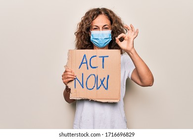 Middle Age Woman Wearing Coronavirus Protection Mask Holding Act Now Protest Cardboard Doing Ok Sign With Fingers, Smiling Friendly Gesturing Excellent Symbol