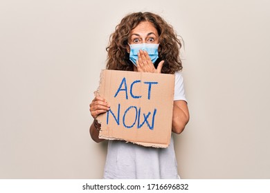 Middle Age Woman Wearing Coronavirus Protection Mask Holding Act Now Protest Cardboard Covering Mouth With Hand, Shocked And Afraid For Mistake. Surprised Expression