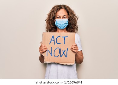 Middle Age Woman Wearing Coronavirus Protection Mask Holding Act Now Protest Cardboard Looking Positive And Happy Standing And Smiling With A Confident Smile Showing Teeth