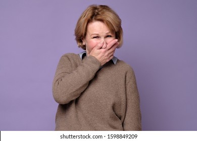 Middle age woman wearing sweate laughing and embarrassed giggle covering mouth with hands, gossip and scandal concept - Powered by Shutterstock