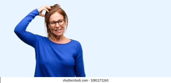 Middle age woman wearing wool sweater and glasses doubt expression, confuse and wonder concept, uncertain future isolated blue background