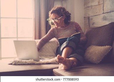 Middle Age Woman Working At Home Sit On The Sofa Using A Laptop. Barefoot Relax With Backlight Atmosphere.