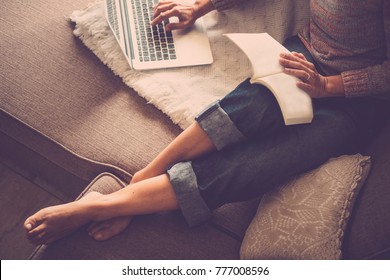 Middle Age Woman Working At Home Sit On The Sofa Using A Laptop. Barefoot Relax With Backlight Atmosphere.