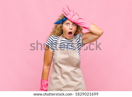 middle age womanraising palm to forehead thinking oops, after making a stupid mistake or remembering, feeling dumb housekeeper concept