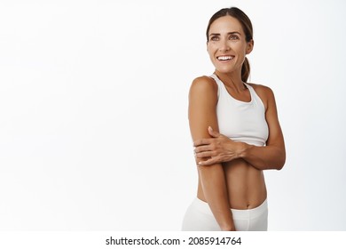 Middle aged 30 years old fitness woman with fit and strong body, abs and muscles, looking aside happy and smiling, exercise in gym, workout indoors, white background