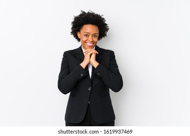 Middle Aged African American Business  Woman Against A White Background Isolated Keeps Hands Under Chin, Is Looking Happily Aside.