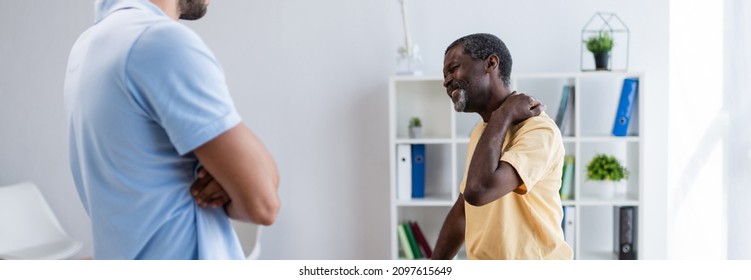 Middle Aged African American Man Suffering From Neck Pain While Talking To Physiotherapist, Banner