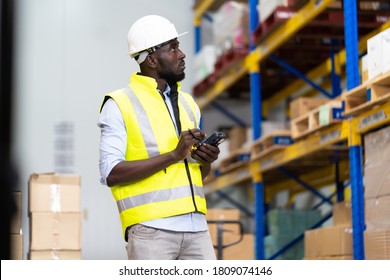 Middle Aged African American Warehouse Worker Preparing A Shipment In Large Warehouse Distribution Centre