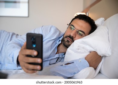 Middle Aged Arab Man In Bed With His Phone Looking At Social Media