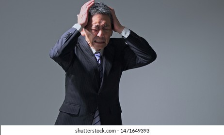 Middle Aged Asian Businessman Having A Head Ache. Brain Stroke Concept. Cerebral Hemorrhage.