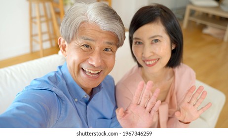 Middle Aged Asian Couple Taking Selfie In The Living Room