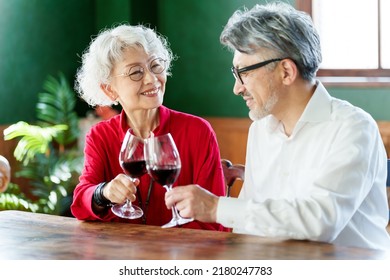 Middle Aged Asian Couple Toasting With Red Wine