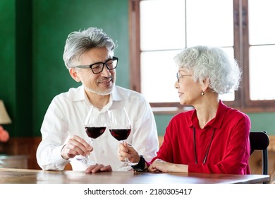 Middle Aged Asian Couple Toasting With Red Wine