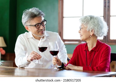 Middle Aged Asian Couple Toasting With Red Wine