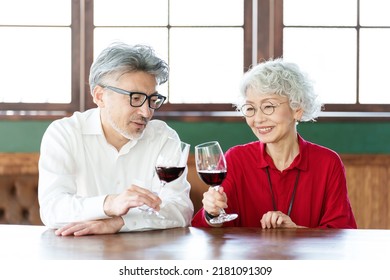 Middle Aged Asian Couple Toasting With Red Wine