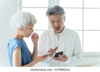 Middle Aged Asian Couple Using Smart Phone