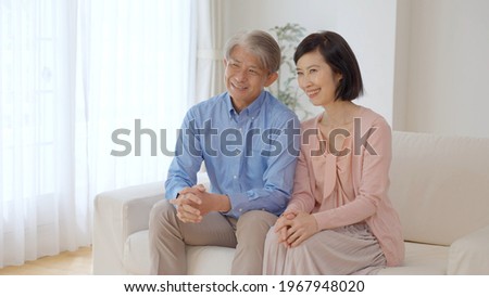 middle aged asian couple watching movie in the living room