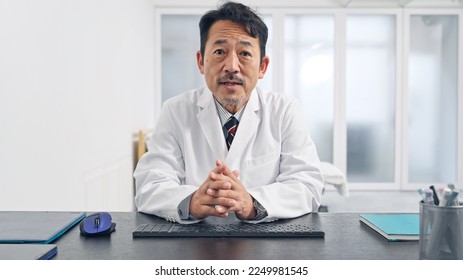 Middle aged Asian doctor talking with video call. - Powered by Shutterstock