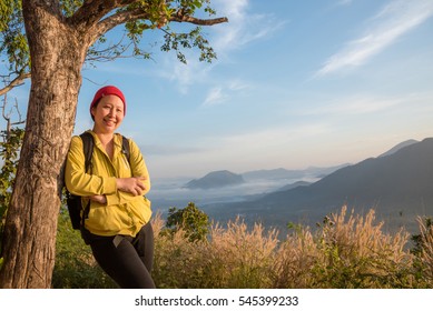 Middle Aged Asian Hiker Woman With Backpack Standing And Smiling On The Hill In Morning