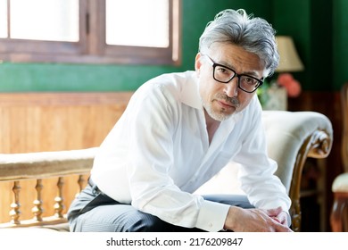 Middle Aged Asian Man With Gray Hair Relaxing On Sofa