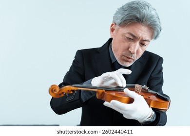 middle aged asian man inspecting violin