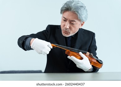 middle aged asian man inspecting violin