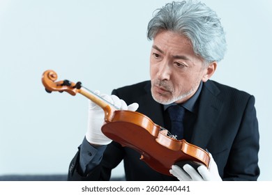 middle aged asian man inspecting violin